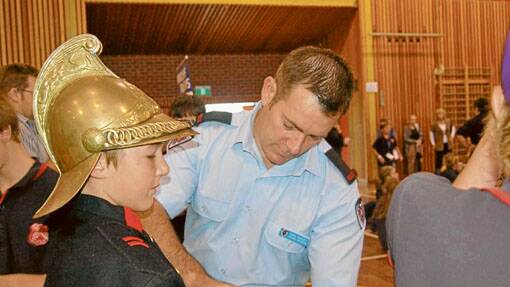Chris Howard from the Boorowa Fire Brigade helps Bailey Howard try on an old uniform. 