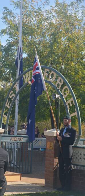 Corporal Scott Cox takes over flag bearing duties from Ross Williams at this year's Anzac Day March. Photo by John Snelling. 