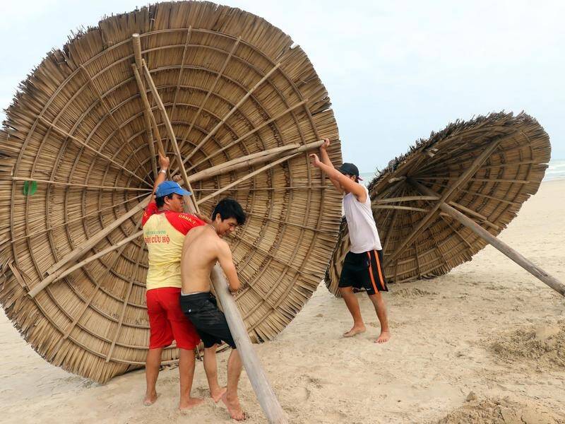 People remove thatched beach shades ahead of the arrival of Typhoon Molave, in Danang, Vietnam.
