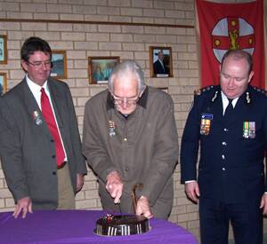 Jack O’Malley, the longest serving member of the Frogmore Fire Brigade, cuts the brigade’s centenary cake last Friday as Dan Carey and NSW Rural Fire Service Commissioner Shane Fitzsimmons watch on.